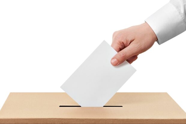 ballot box - hand posting vote in slot