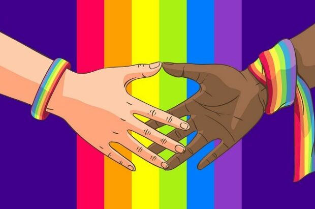 Hands reaching towards each other against background of Pride flag