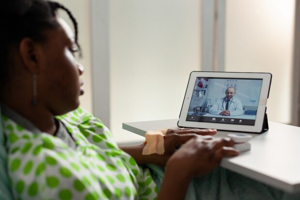 Woman checking her blood sugar levels while having video call with doctor