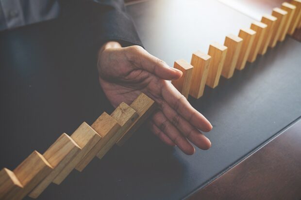 Hand stopping dominos collapsing