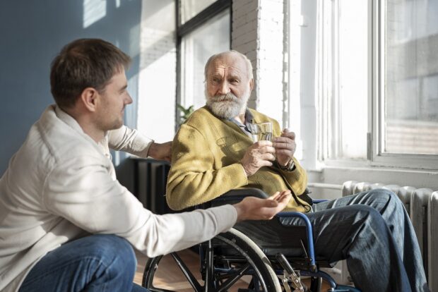 Social worker and older man in wheelchair chatting